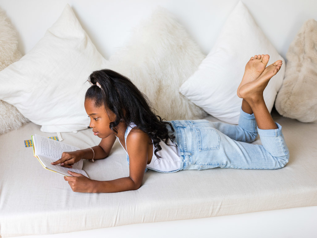 school aged girl reading on couch