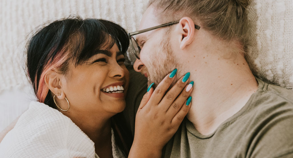 A couple embracing and smiling on a bed