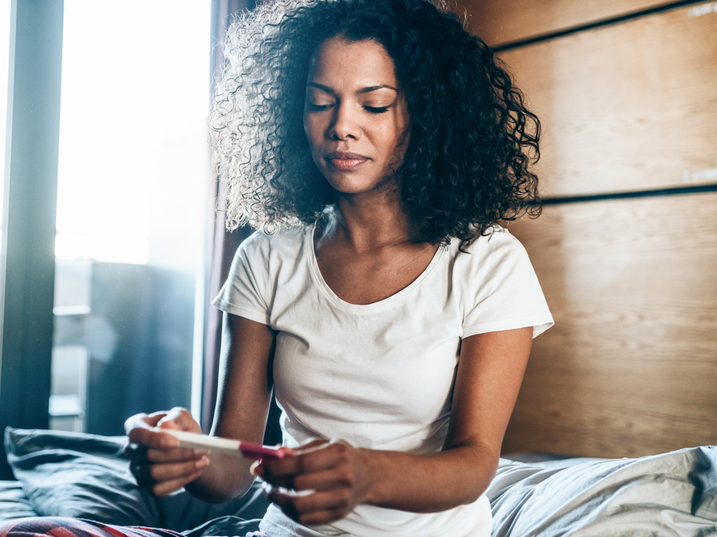 concerned woman looking at pregnancy test