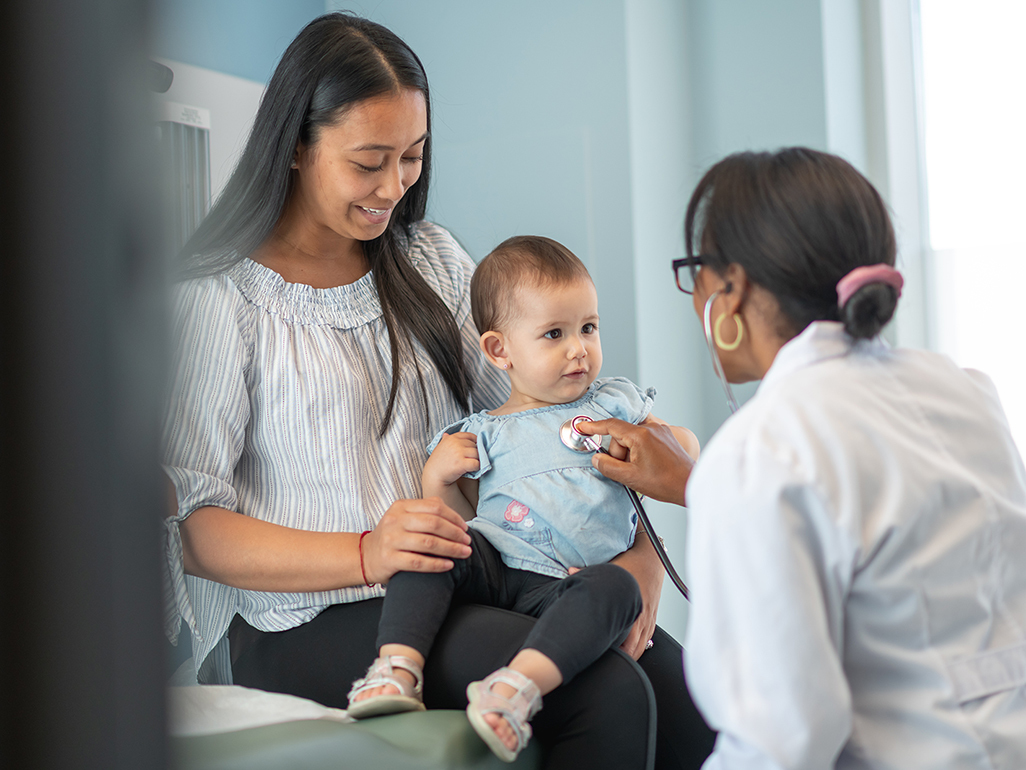 mom holding baby on lap while doctor examines baby