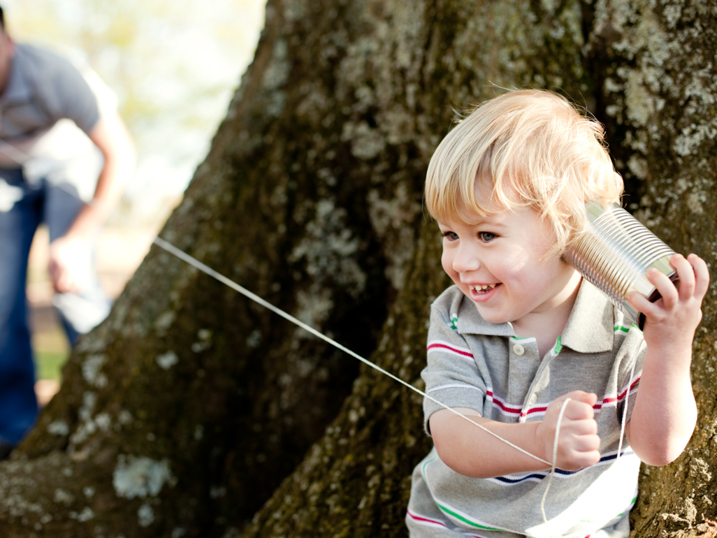 A father and child talking to each other through tin cans tied with string