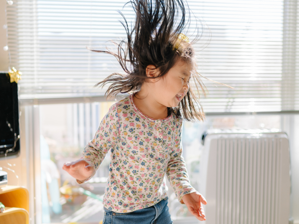 little girl dancing happily while swinging hair