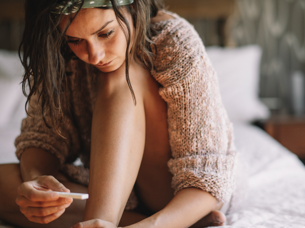 woman looking puzzled holding home pregnancy test