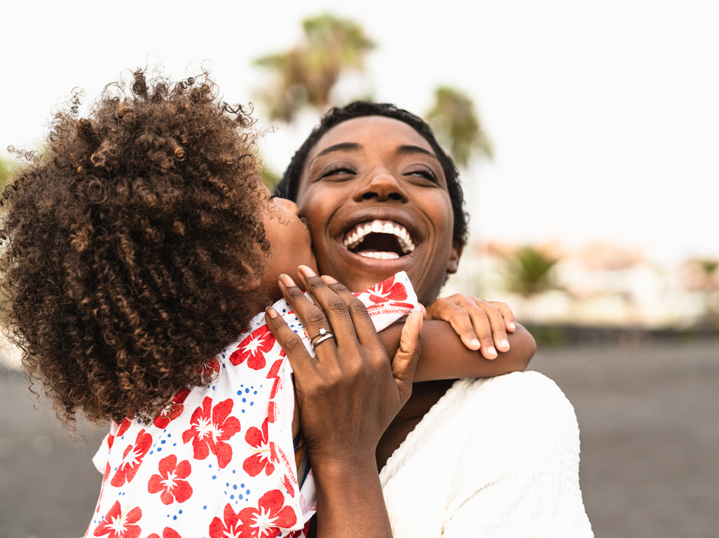 mother smiling with joy while child kisses her cheek