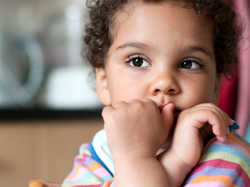 A toddler covering their mouth with their hands