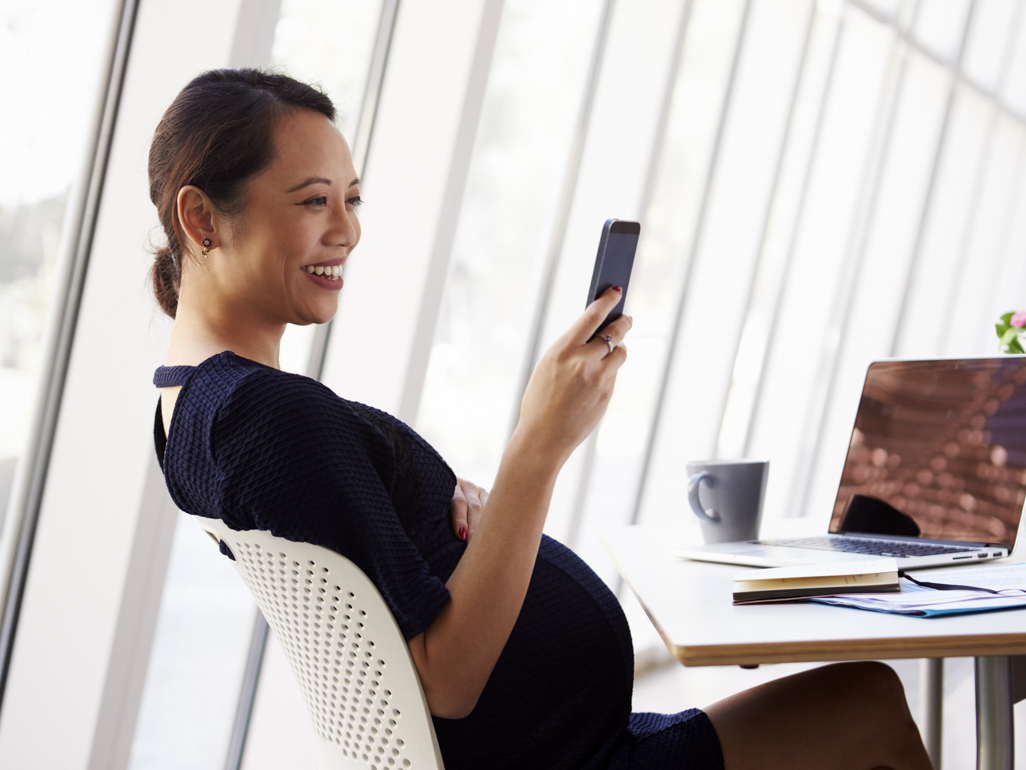 pregnant woman at work looking at her phone