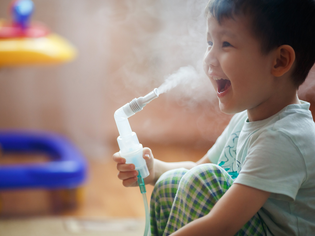 happy little boy using breathing nebulizer