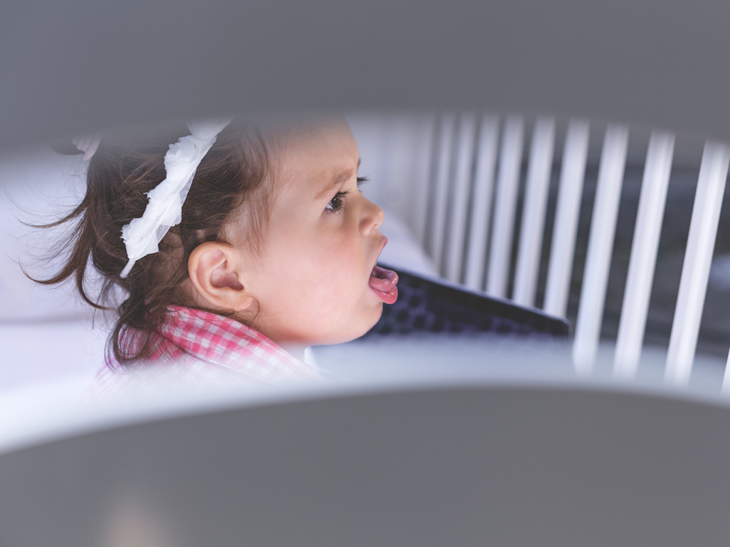 little girl coughing in her crib