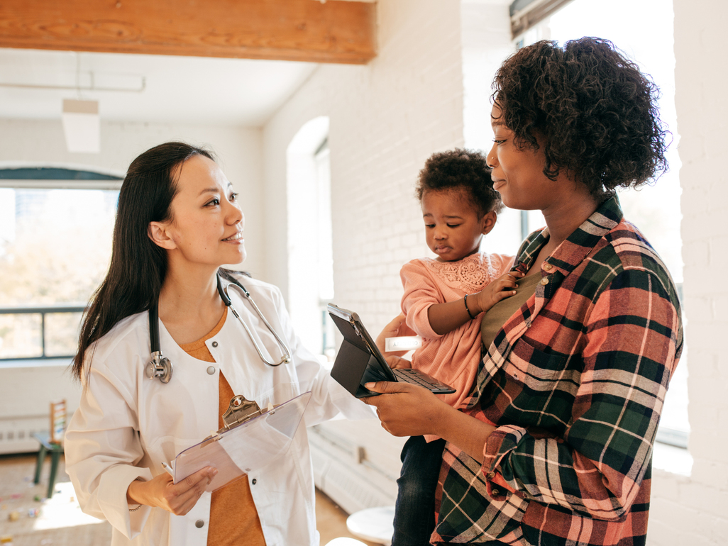 mom holding sick baby and talking to pediatrician 