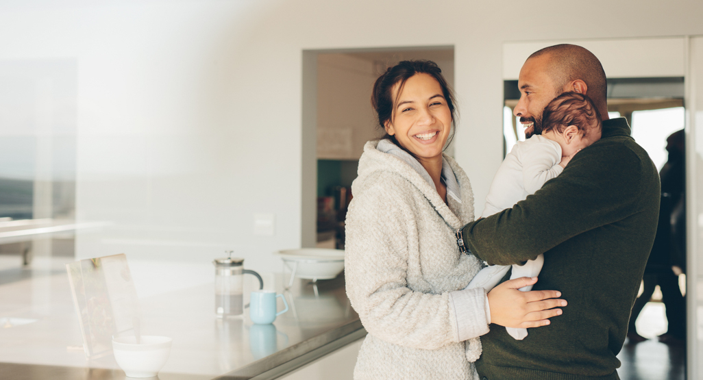 new mother smiling as dad holds baby