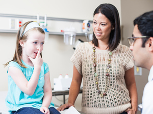 child being examined at the clinic, pressing her index finger on the tip of her nose