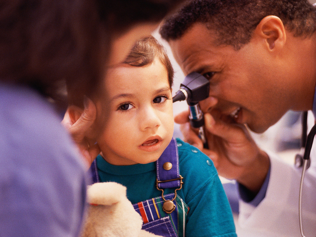 doctor examining an ear of a boy with an otoscope