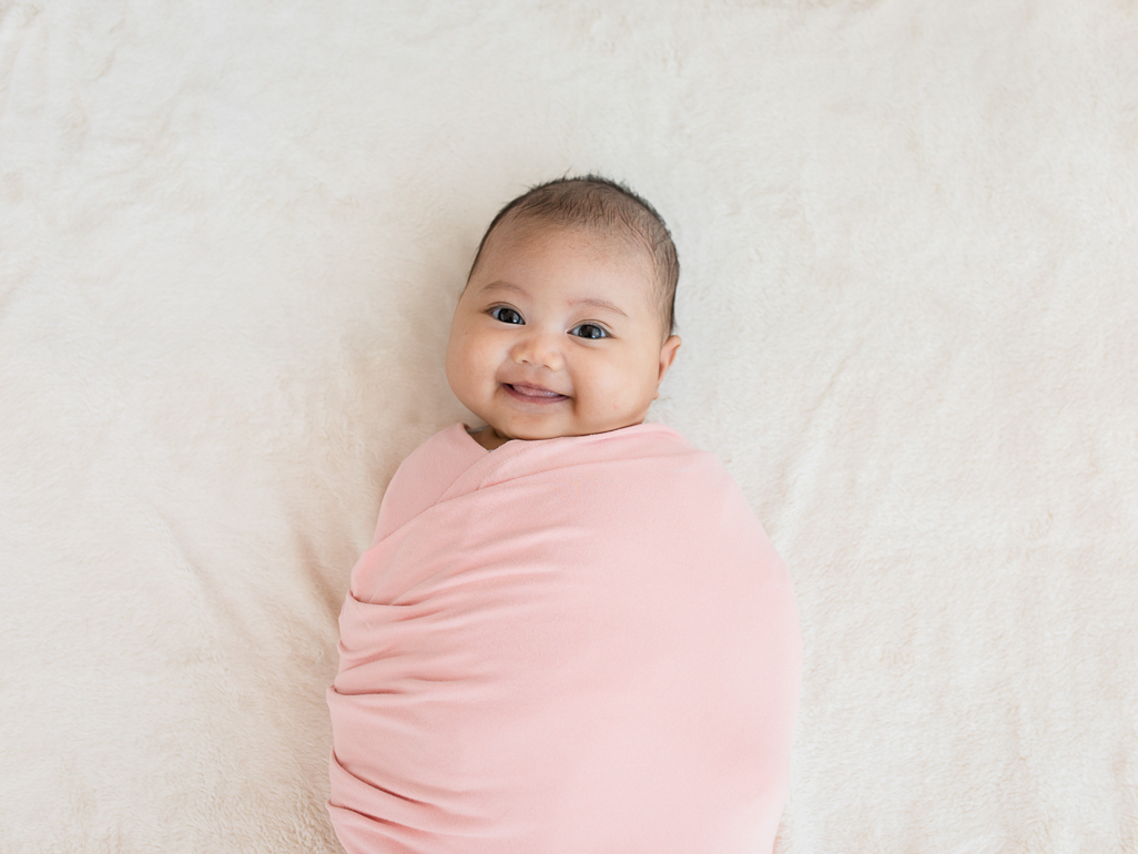 smiling baby swaddled in pink blanket